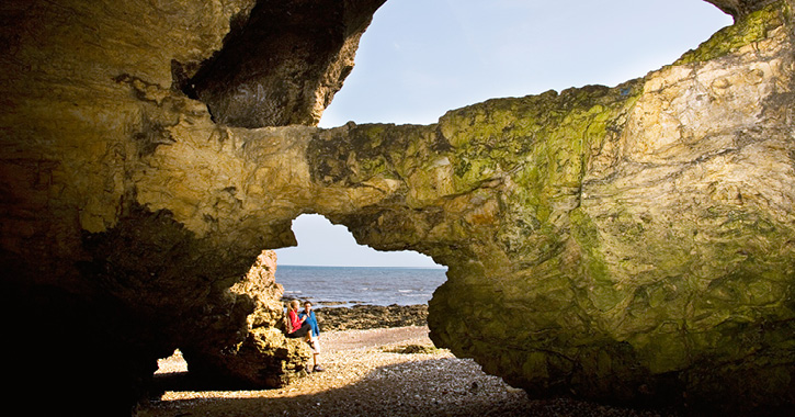 couple walking through sea cave at Blackhall Rocks Beach, County Durham
